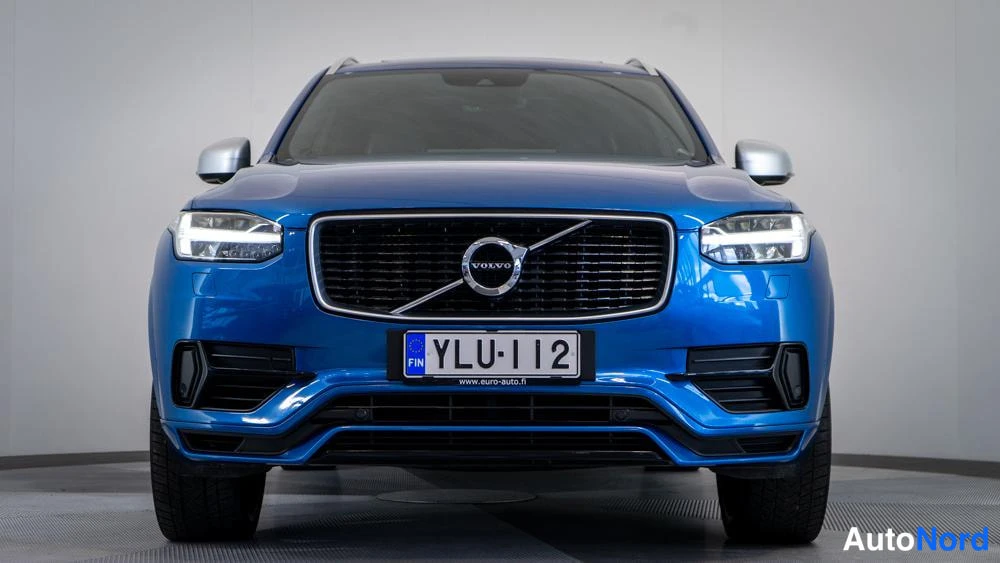 Edestä: Suoraan edestä kuvattu Volvo XC90. Ruoentaulussa on teksti FIN. LED-tunnelit ovat päällä, kuten myös Volvo-logo ruuhdossa ja suuri etusuoja.