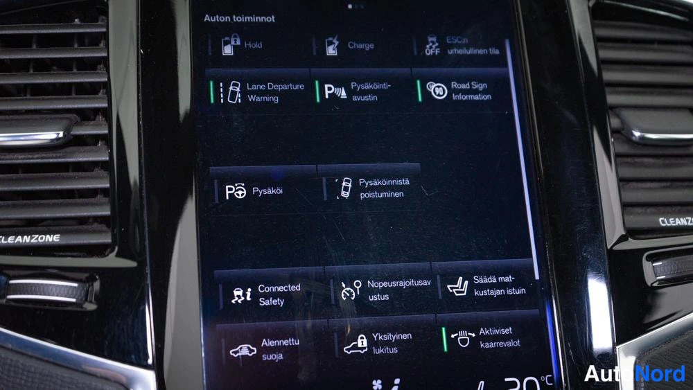 Muu: Infotainment-näytön 'Auton toiminnot' -valikko, jossa kohteita kuten Lane Departure Warning, Pysäköinti-avustin, Road Sign Information, Nopeusrajoitusavustus ja