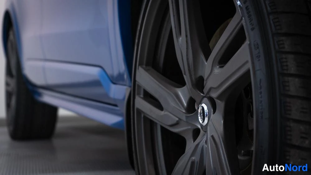Yksityiskohta: Lähikuva autosta: yksi pyörä osoittaa kevytmetallivanteet ja renkaat. Pyörän keskipisteessä on Volvo-logo. Renkaan sivussa on tekstiä, jossa näkyy 'M+S' talvire