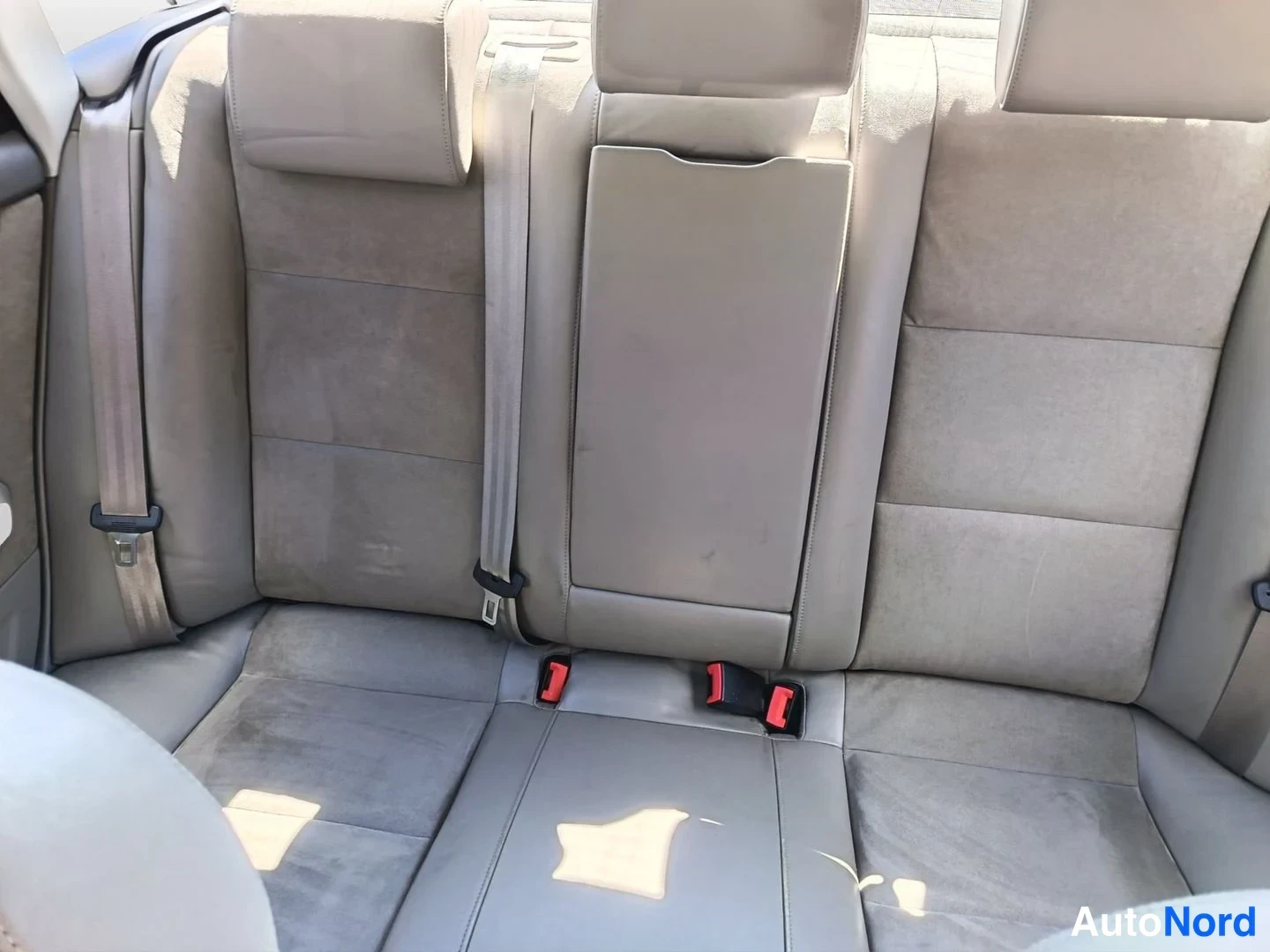Takaistuimet: Tarkempi näkökulma takapenkistä. Harmahtavat istuimet ja pinnastuslevyt ovat kuluneet. ISOFIX-kiinnikkeet ovat keskellä penkkiä.