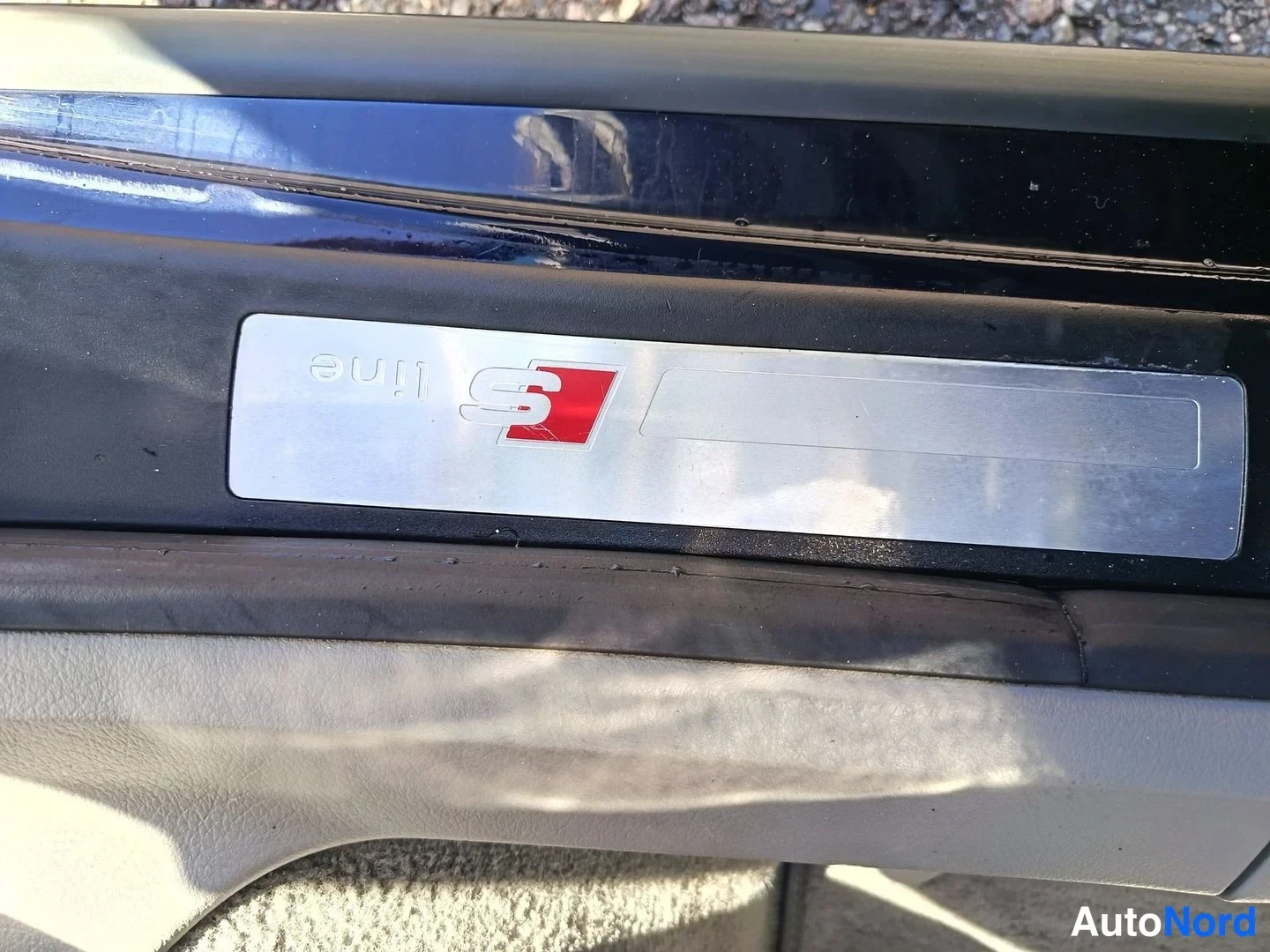 Yksityiskohta: Kuvassa on S-Line-logo auton ovikynnyksessä. Logolla on punainen taustalla oleva ruutu ja valkoinen S-muotoilu.