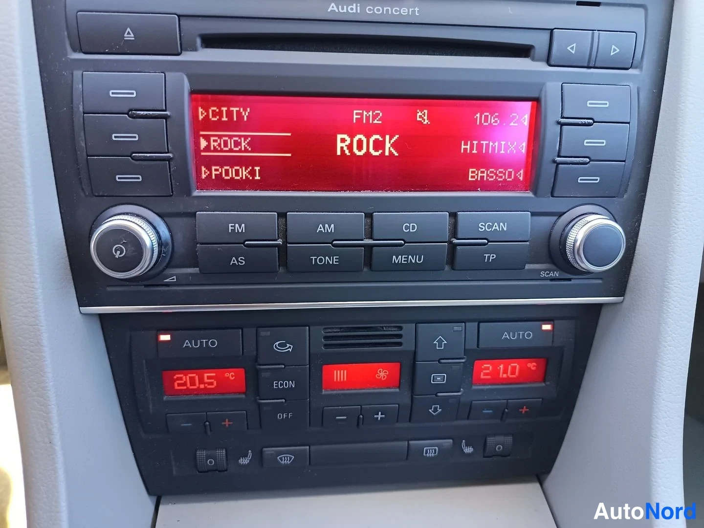 Muu: Audi concert -radiolla näkyy FM2-taajuus 106.2 ja ROCK, alapuolella kaksivyöhykeilmastointi: AUTO 20,5 °C ja 21,0 °C, ECON- ja OFF-napit.