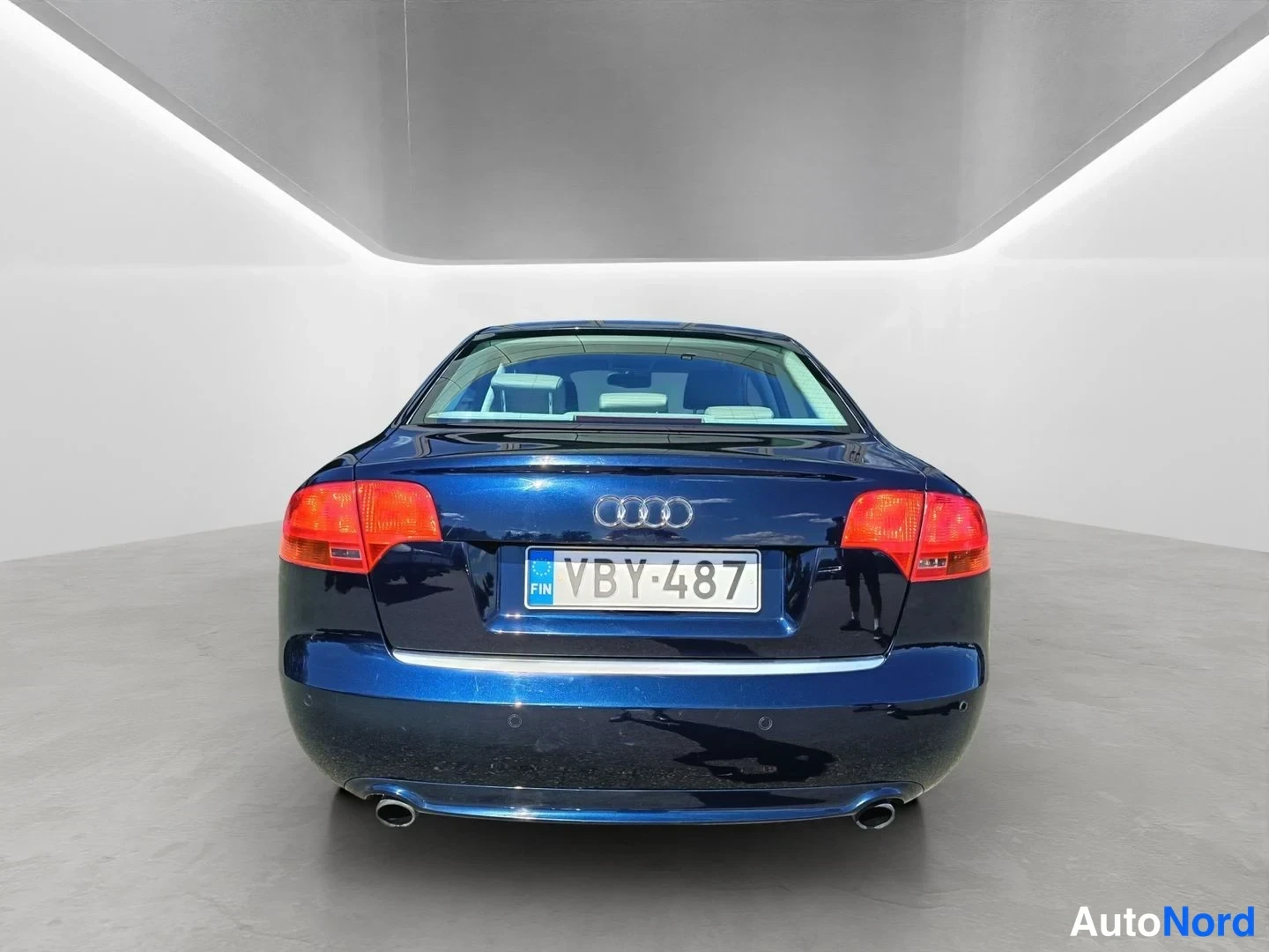 Takaa: Suora takanäkymä tummansinisestä Audi-hatchback-autosta. Kahdessa putkiputkessa näkyvät pakoputket ja rekisterinumero ovat keskellä.