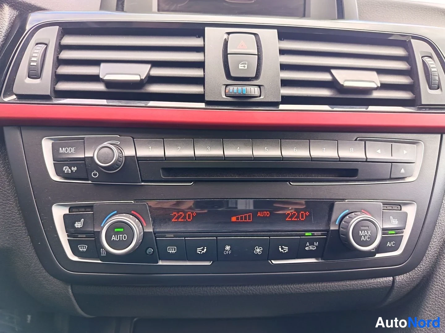 Muu: Kojelaudan keskusta: punainen koristelista, radio/MODE-nappi, numeronäppäimet 1–8 ja kaksivyöhyke ilmastointi näyttäen 22,0 astetta AUTO-tilassa.