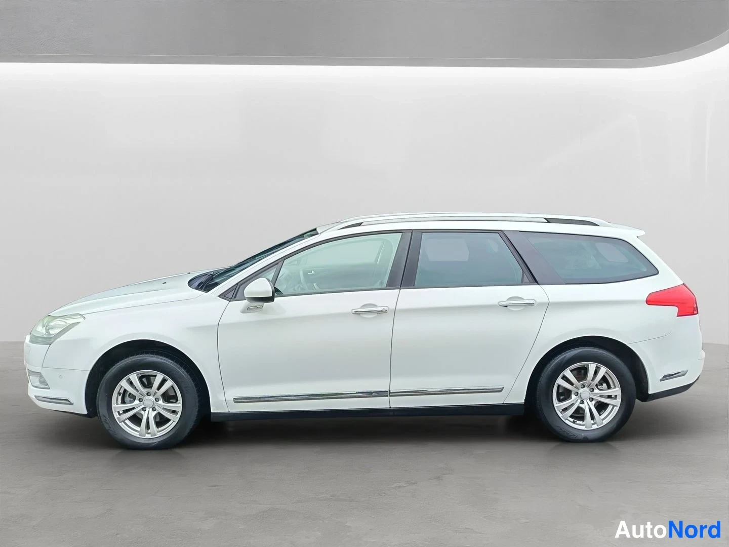 Sivulta: Valkoinen Citroen C5 Tourer -farmari sivulta kuvattuna studiossa, koko auton kylki näkyvissä.