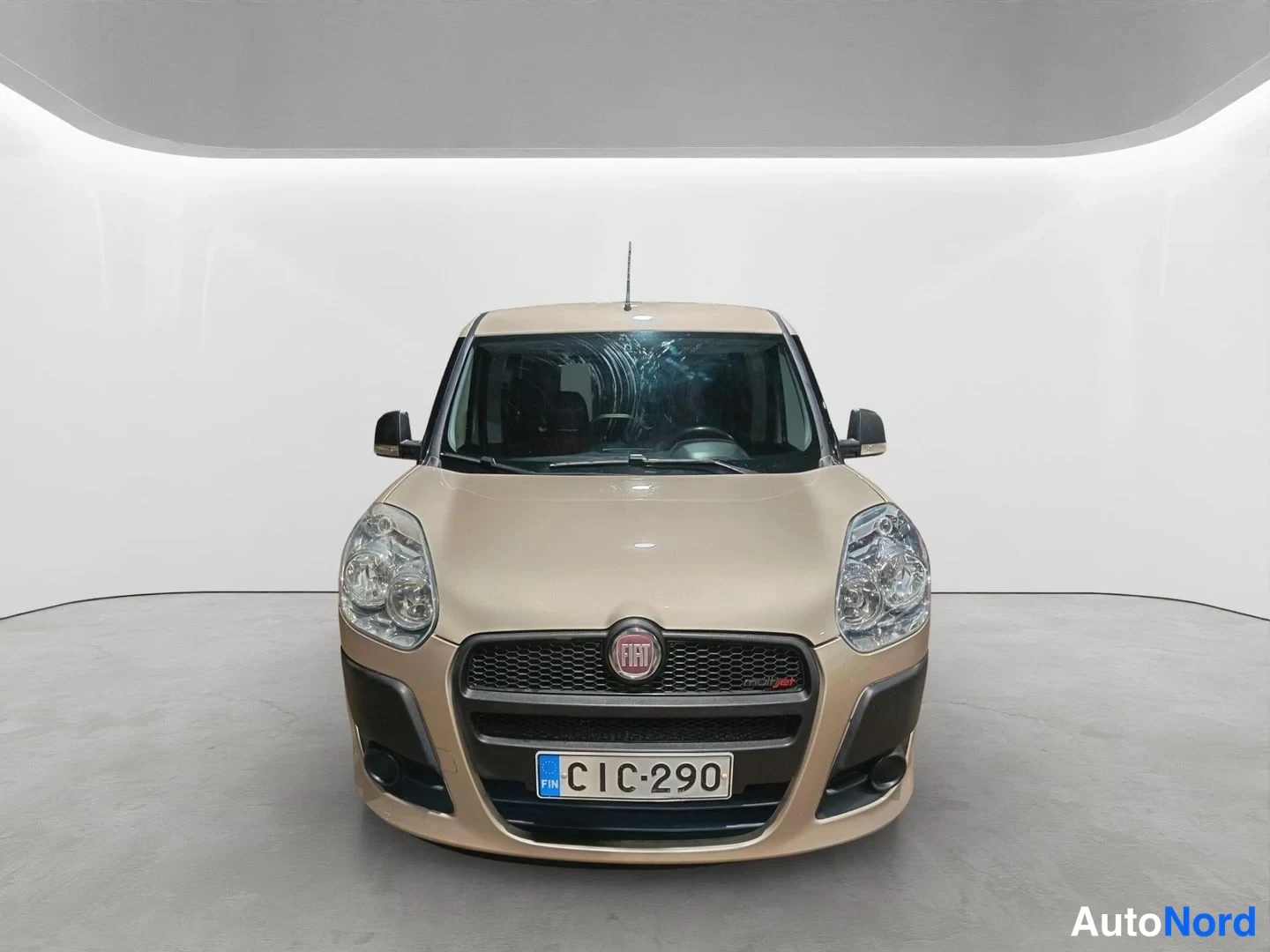 Edestä: Fiat Doblo suoraan edestä, Fiat-merkki ja rekisterikilpi, vaalean beige.