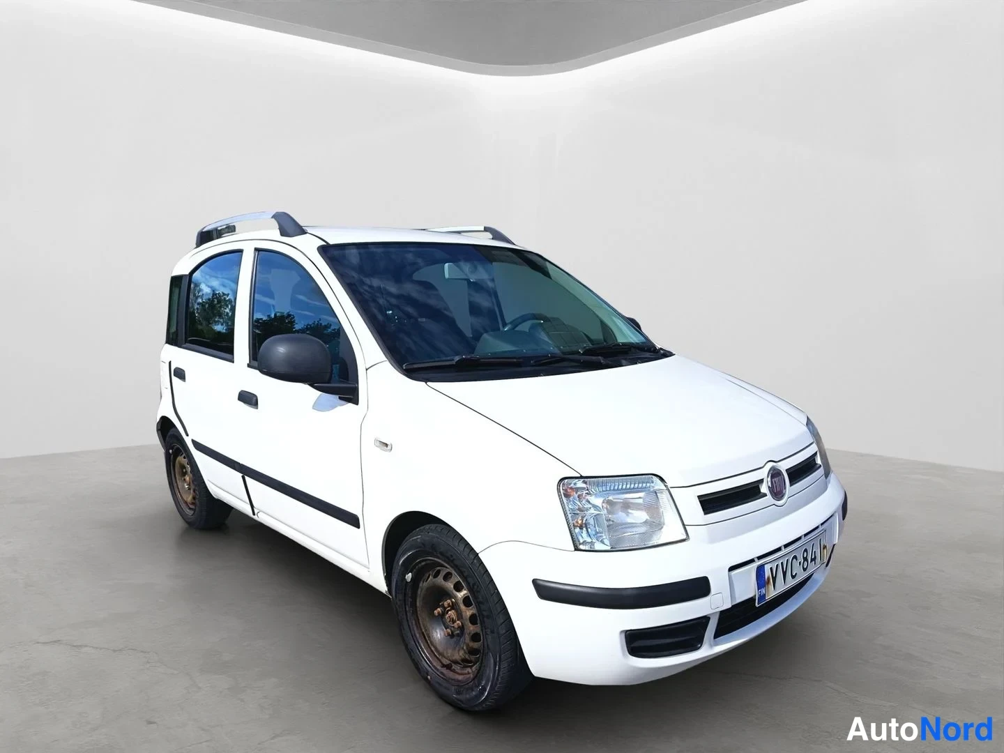 Etuviisto, nokka oikealle: Valkoinen Fiat Panda kuvattu oikeasta etukulmasta; rekisteritunnus ja kattotelineet näkyvissä.