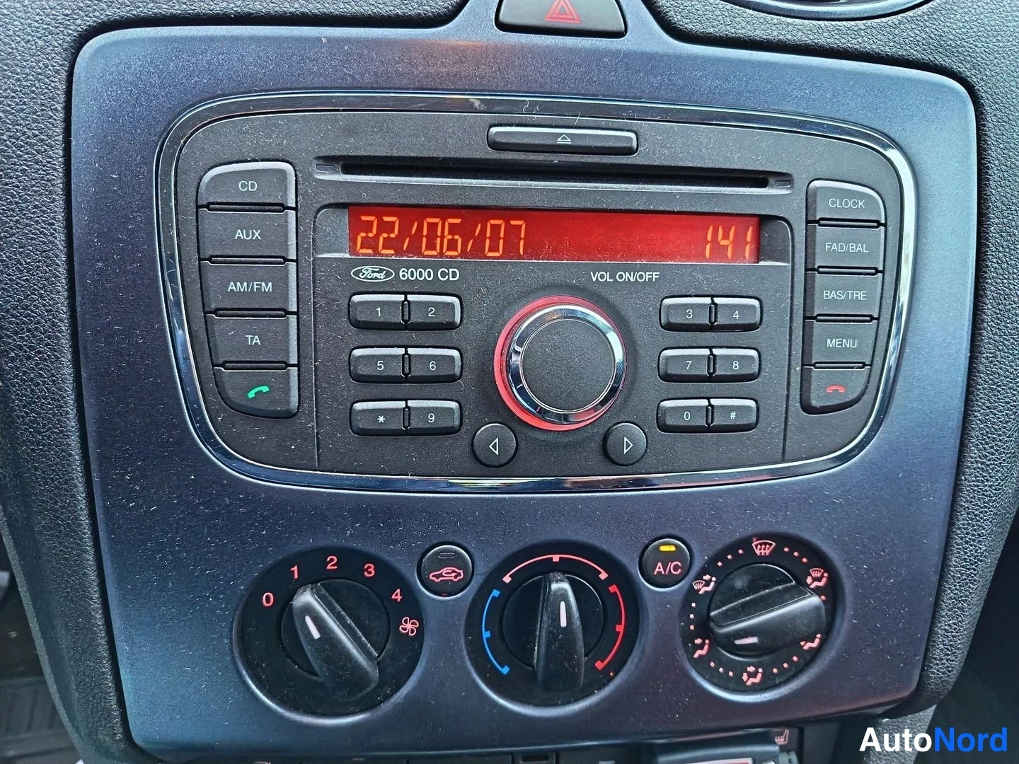 Yksityiskohta: Ford 6000 CD -radiolla varustettu kojelaudan keskikonsoli: näytössä 22/06/07 ja 141, alla ilmastoinnin säätönupit ja A/C-merkki.