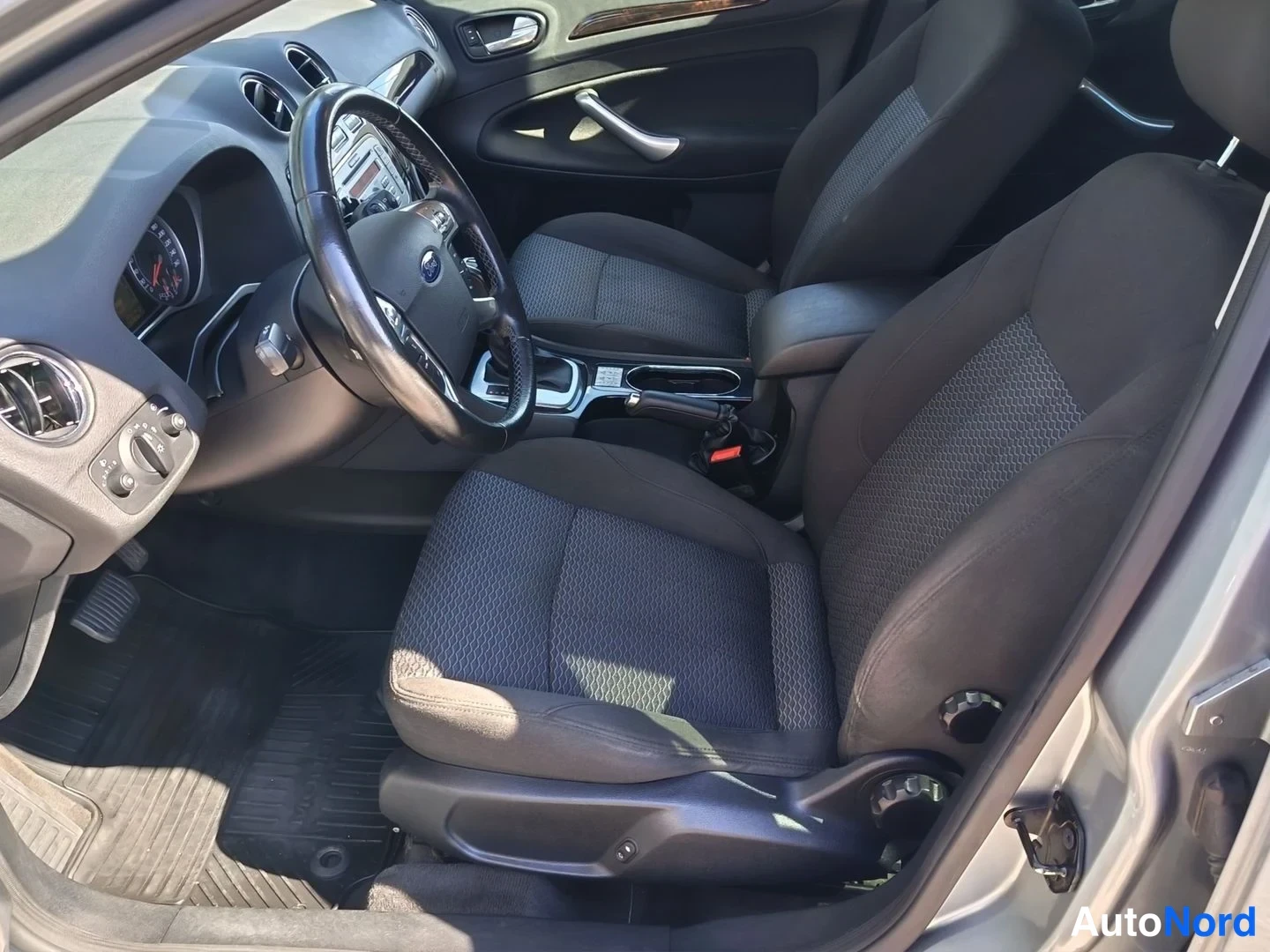 Yksityiskohta: Fordin ohjaamo oikeanpuoleisesta ovesta kuvattuna: kangasistuimet, ratissa Ford-merkki ja automaattivaihteiston valitsin keskikonsolissa.