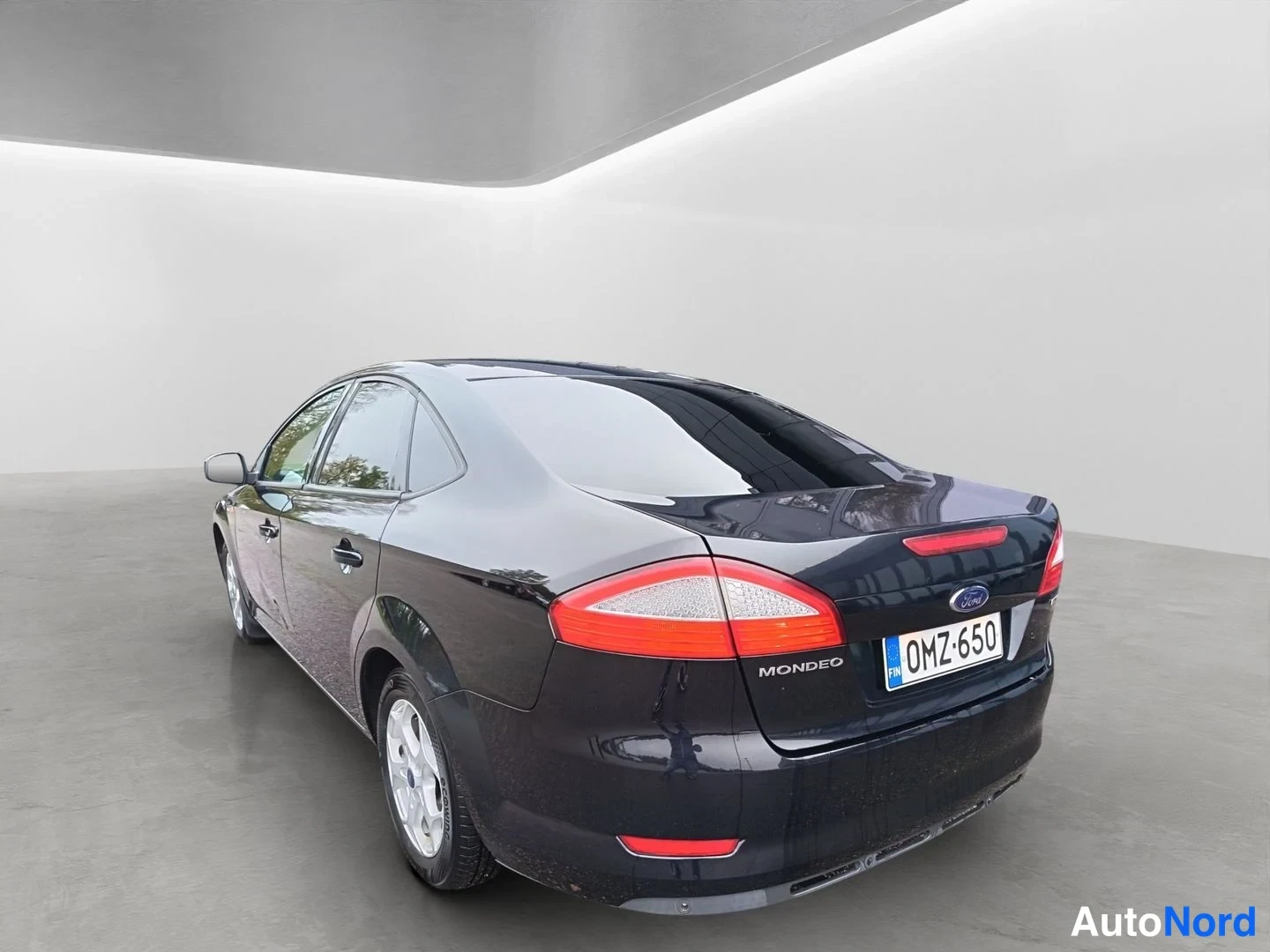 Takaviisto: Ford Mondeo -henkilöautin takakulmasta takaviistosta, tummansininen koripinta, takavaloissa ja Mondeo-teksti näkyvissä.