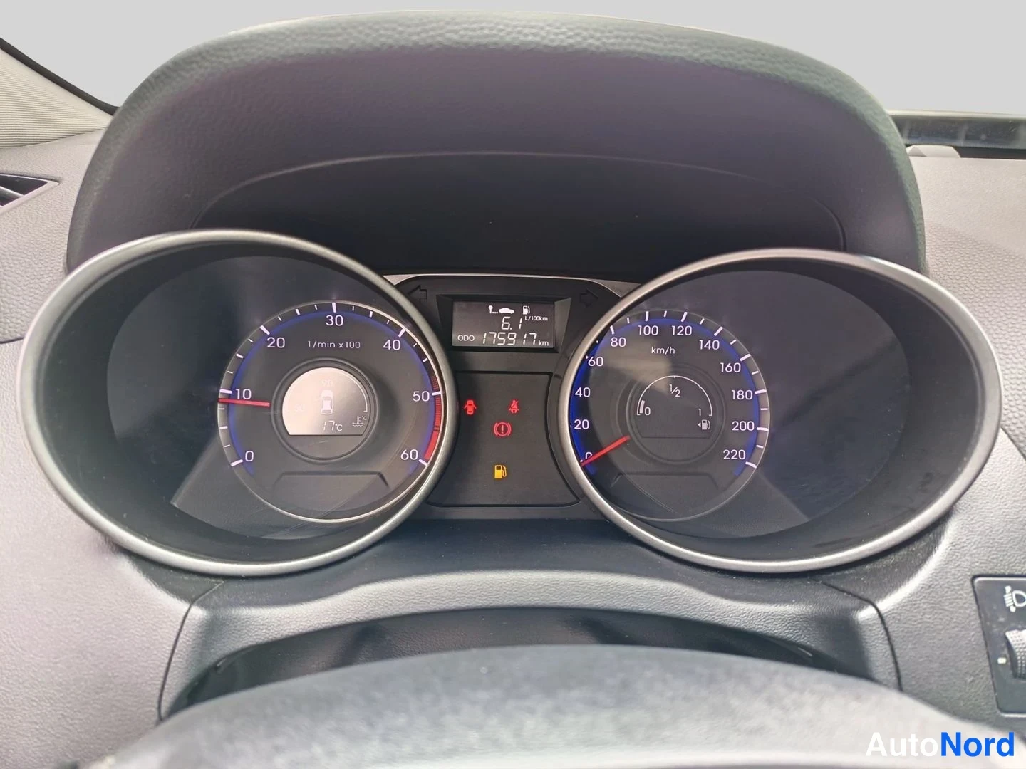 Sivulta: Henkilöauton kojelaudan mittaristo lähikuvassa: kierroslukumittari vasemmalla, nopeusmittari (asteikko 0–220 km/h) oikealla ja keskellä LCD-näyttö, jossa lukeva