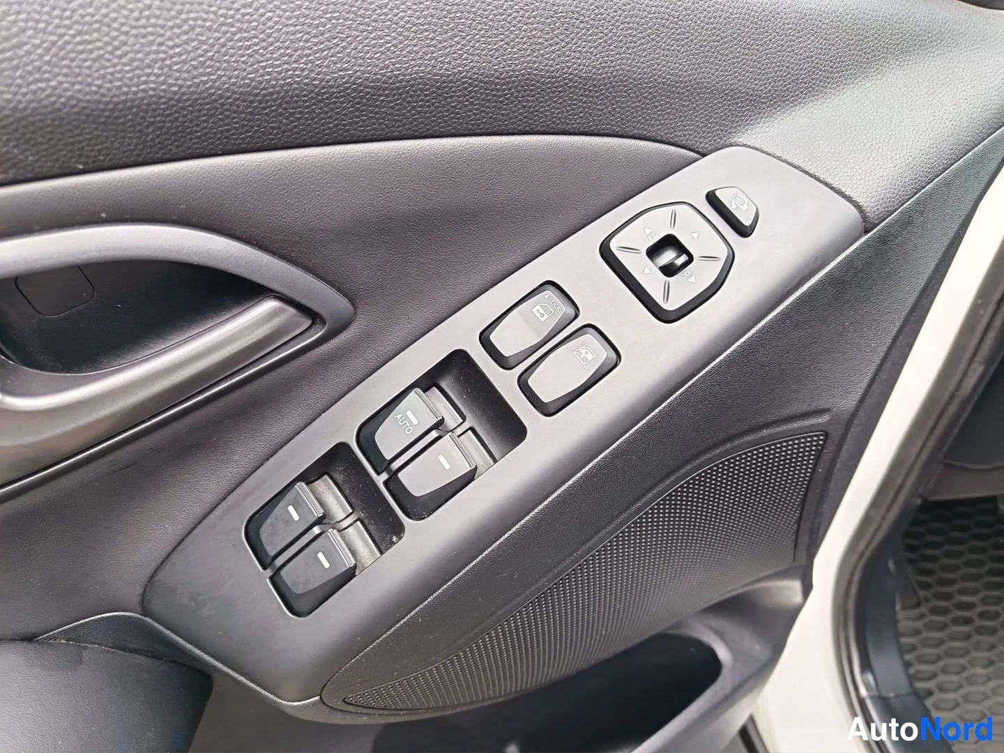 Yksityiskohta: Driver's side door control panel featuring switches for electric window operation with 'AUTO' indicator visible, along with buttons for adjusting the side mirro