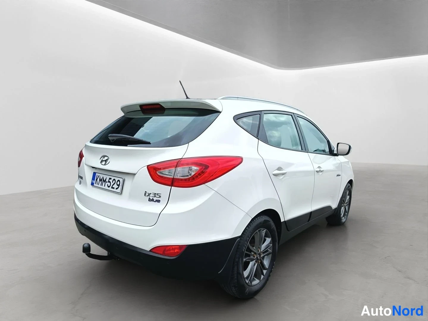 Takaviisto: Hyundai ix35:n takakulmasta vasemmalta kuvattu kuva: valkoinen korinväri, punaiset takavalot, -rekisterikilpi, ix35 blue -merkintä ja vetoautojenostokoulu.