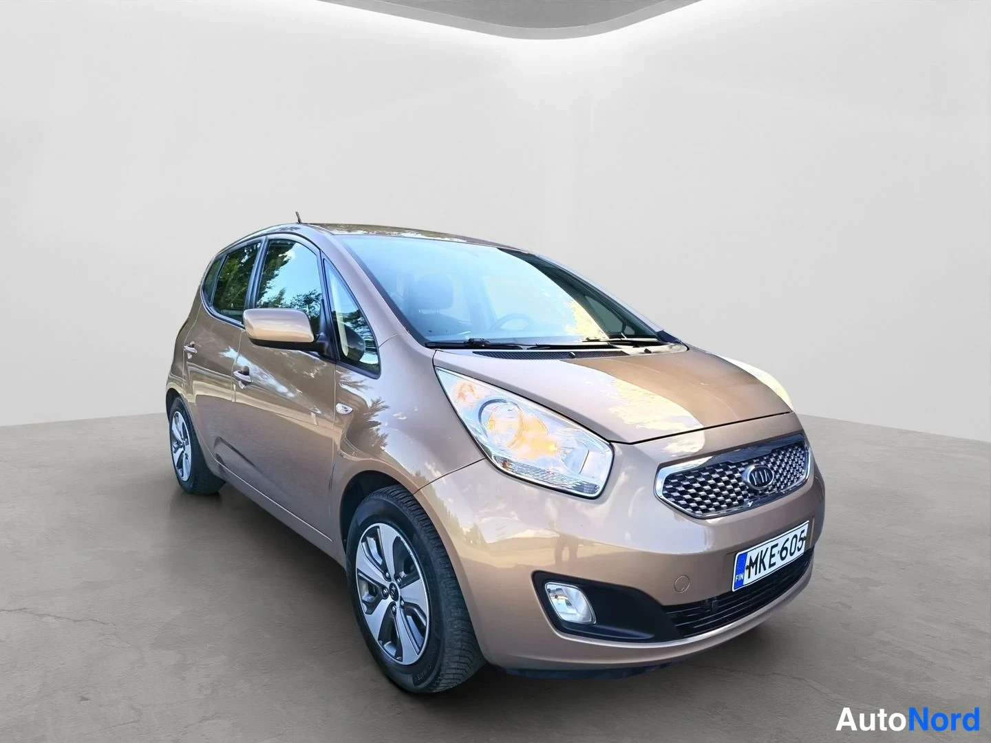 Etuviisto, nokka oikealle: Kia Venga -henkilöauto kulmakuva edestä oikealta, vaaleanbeige koriväri, rekisteritunnus.