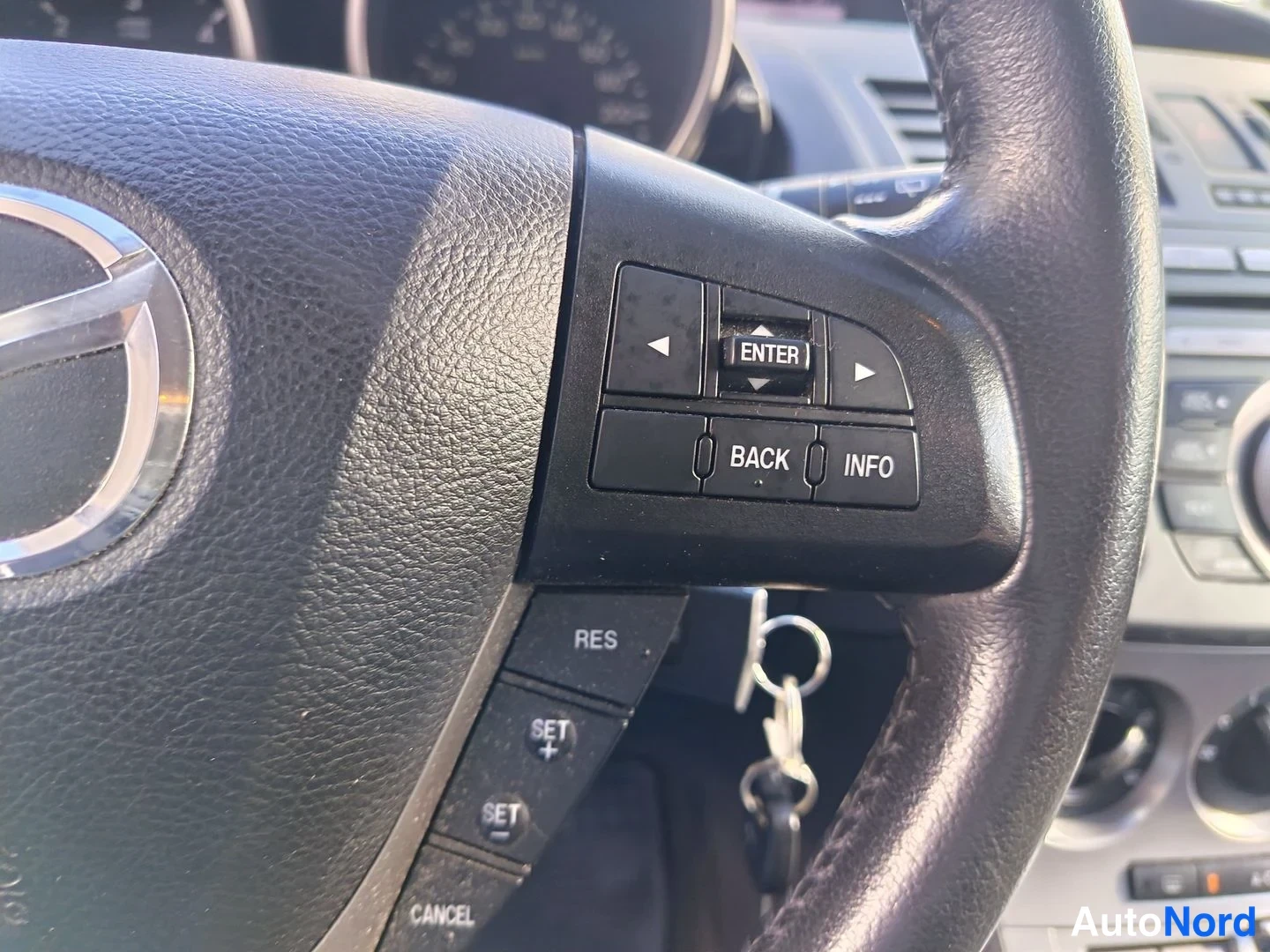 Yksityiskohta: Detailed shot of the right side of the steering wheel controls and ignition area. Menu navigation buttons including directional arrows and 'ENTER' are visible a
