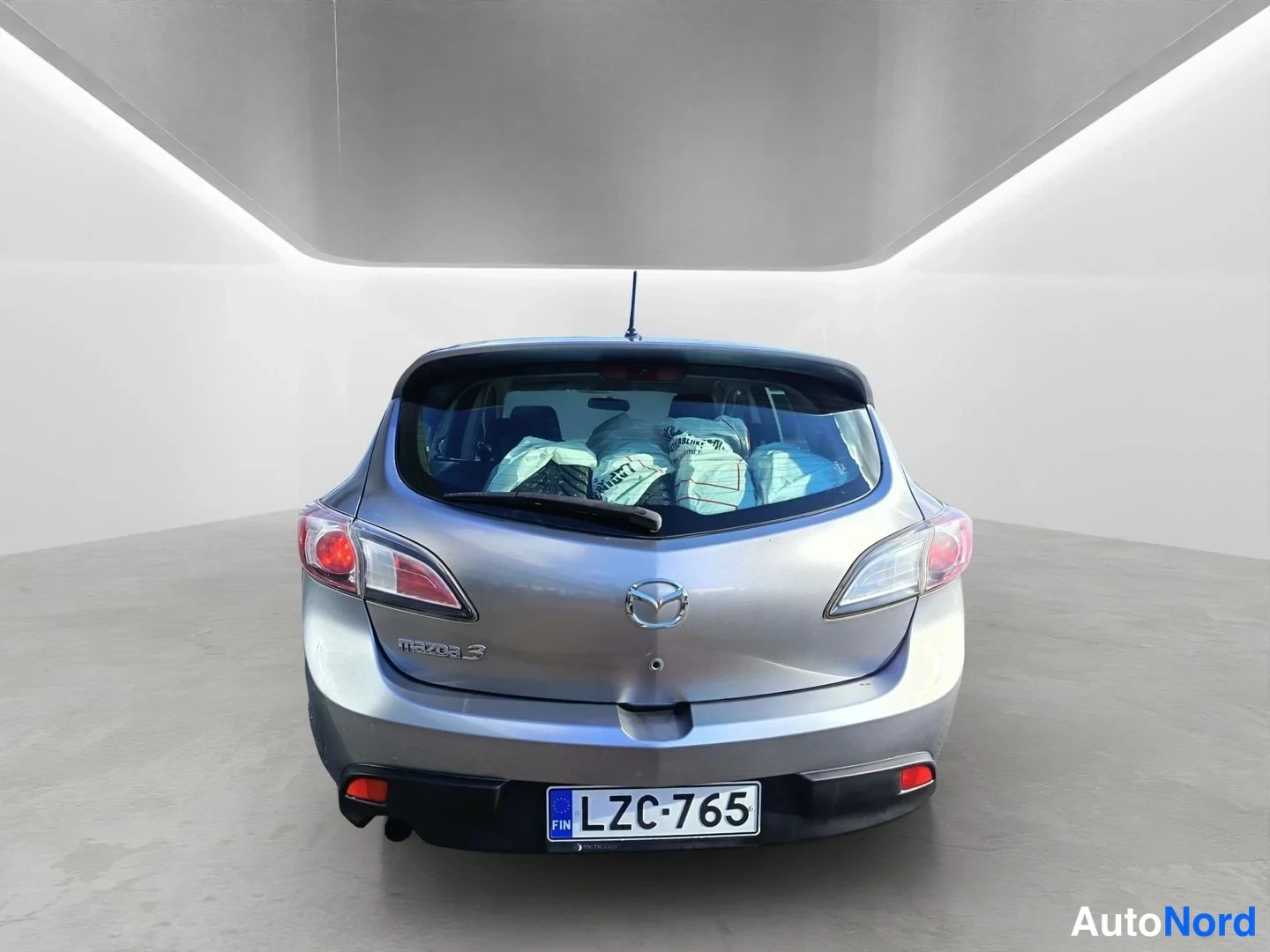 Takaa: Mazda 3:n takaosa suoraan takaa: takavalot, Mazda-merkki, Mazda3-teksti ja rekisteritunnus.