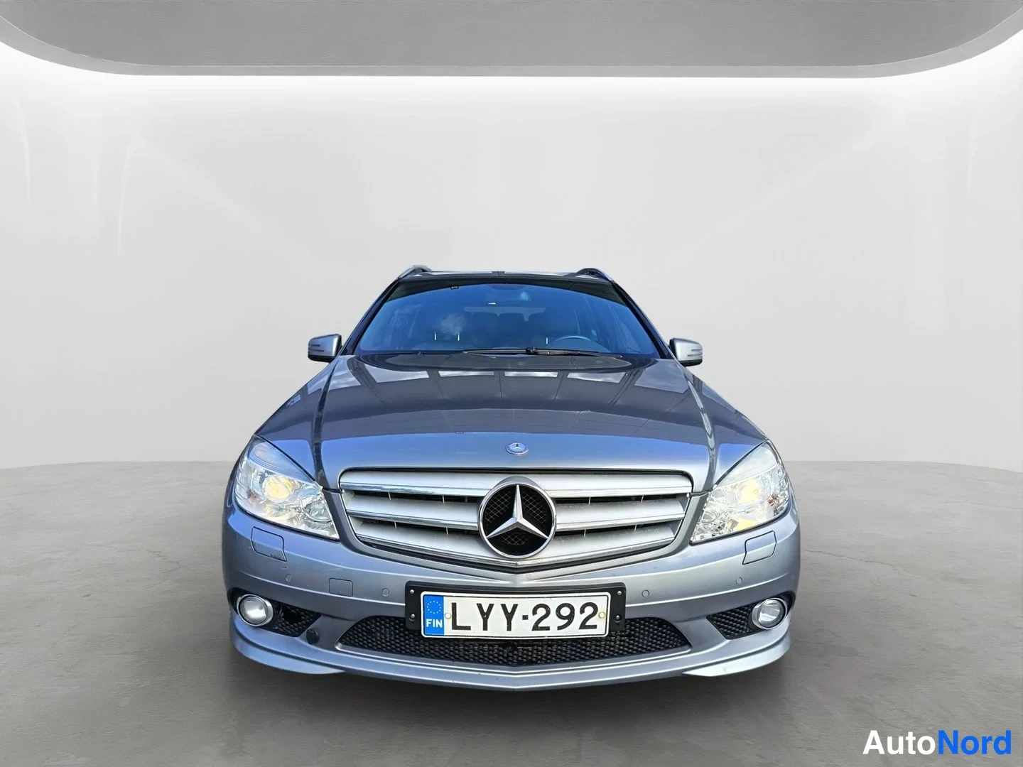 Edestä: Mercedes-Benz C-sarjan farmari suoraan edestä, hopeanharmaa, rekisteritunnus.