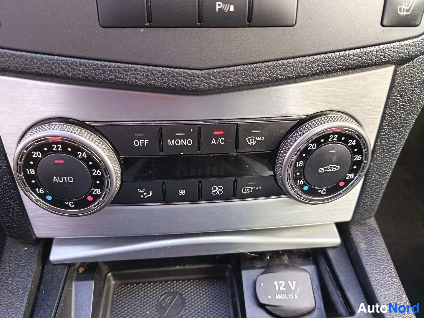 Yksityiskohta: Dual-zone climate controls with two temperature dials set to AUTO mode (left at 21°C, right at 24°C), A/C buttons, fan controls, and an air recirculation settin