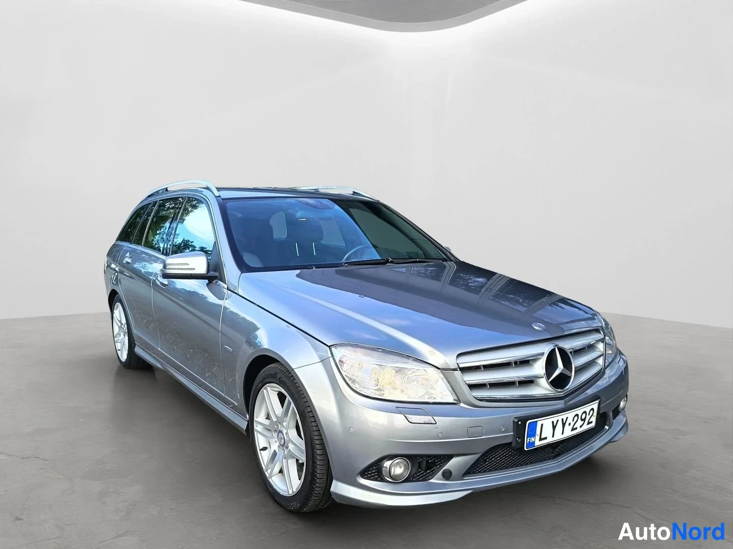 Etuviisto, nokka oikealle: Mercedes-Benz C-sarjan farmari etuviistosta oikealle, hopeanharmaa, rekisteritunnus.