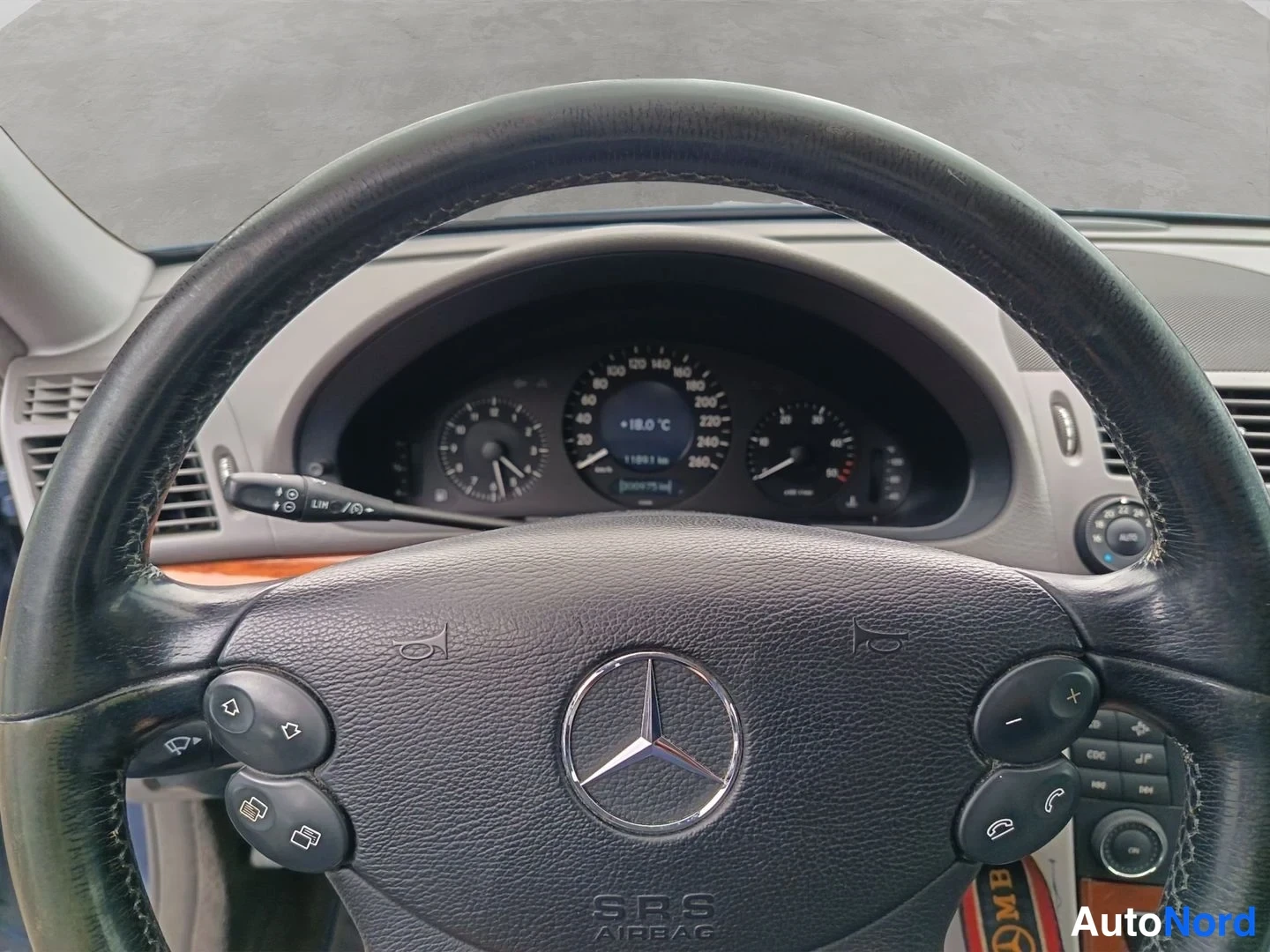 Muu: Lähikuva Mercedes-merkistä ratissa ja mittaristosta, jolla lukema noin 110 921 km.