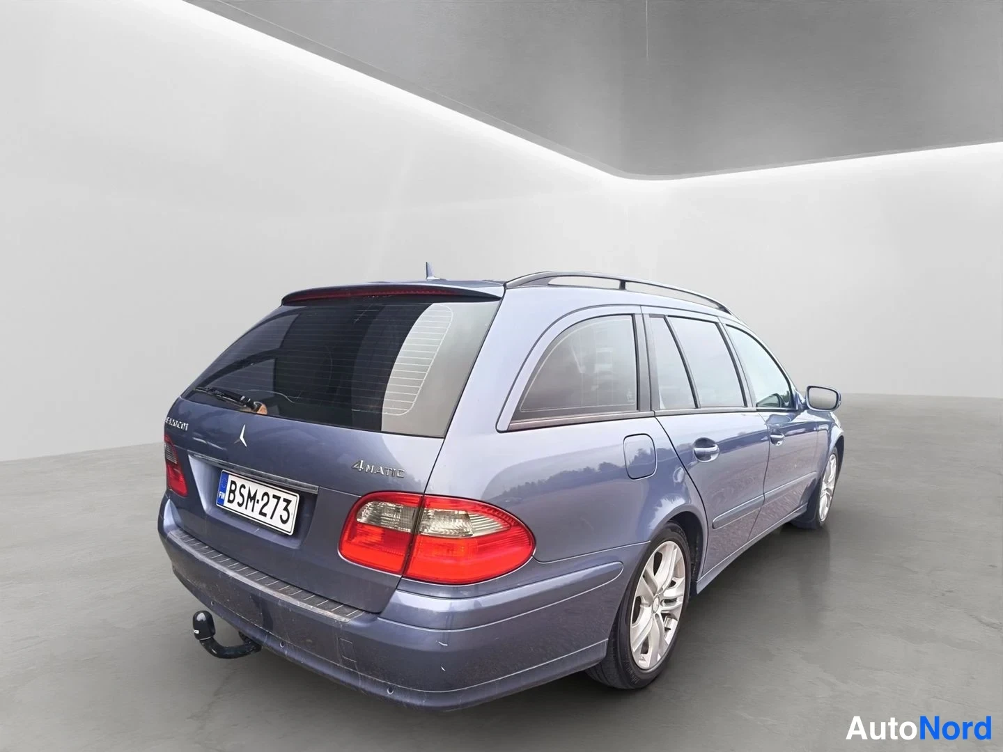 Takaviisto: Sininen Mercedes-Benz E 320 CDI -farmariauto takaviistosta, takavalojen ja rekisterikilven näkyvät