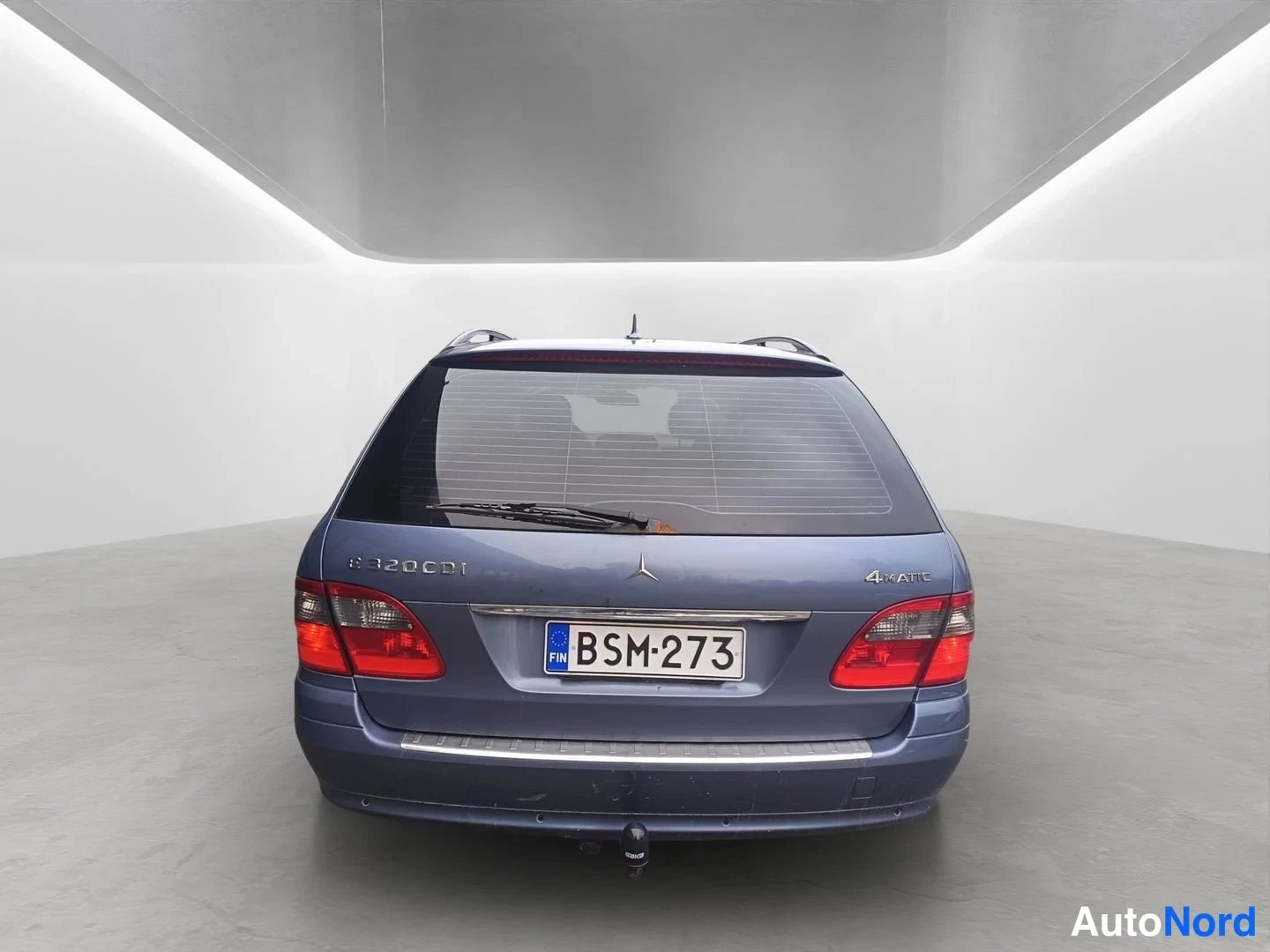 Takaa: Sinisen Mercedes-Benz E 320 CDI -farmarin takaosa suoraan takaa, takalasin lämmityslinjat ja rekisterikilpi näkyvät