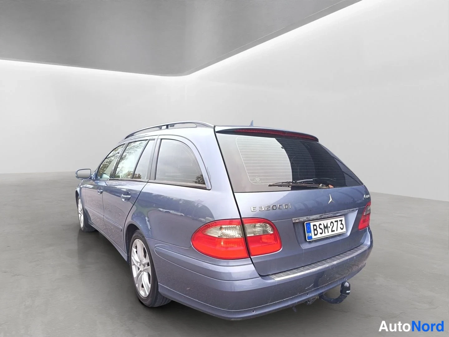 Takaviisto: Sininen Mercedes-Benz E 320 CDI -farmariauto takaviistosta oikealta, E 320 CDI -merkintä ja rekisterikilpi näkyvät