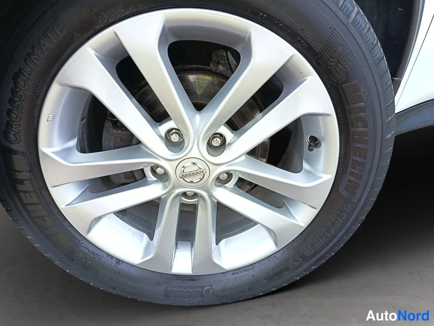 Muu: Nissan-alkuperäinen hopeinen alumiinivanne, renkaassa MICHELIN CrossClimate -merkintä; jarrulevy ja -satula näkyvissä.