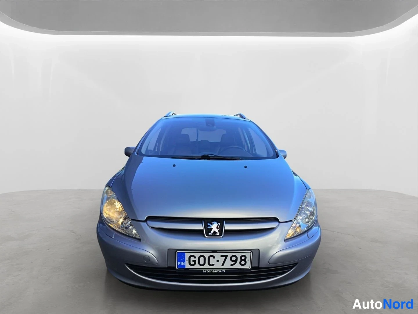 Edestä: Auton etunäkymä suoraan edestä, Peugeot-merkki jäähdytinsuojassa ja rekisteritunnus.