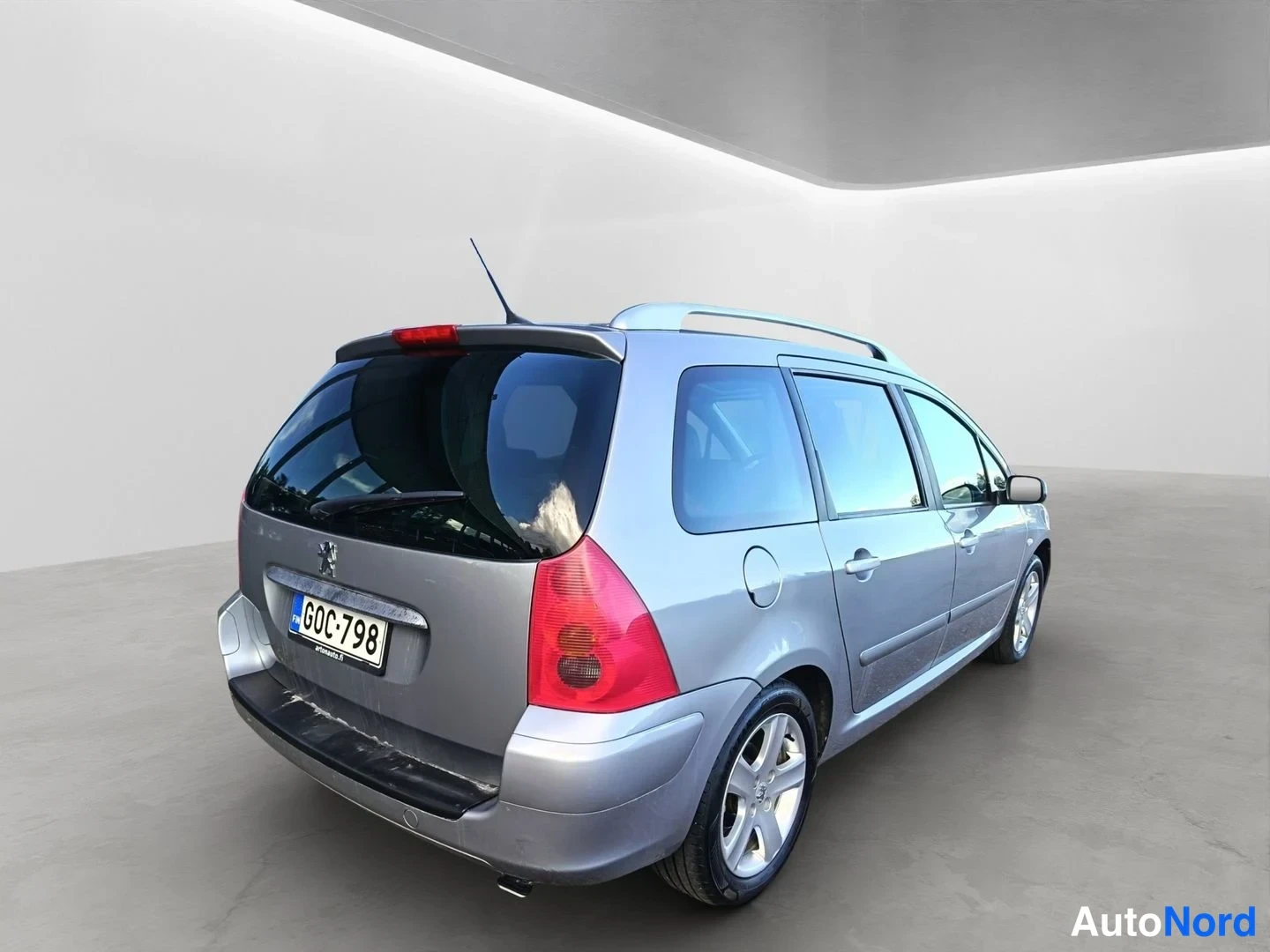 Takaviisto: Peugeot 307 -farmariauto takaa sivusuunnasta kuvattuna; rekisteritunnus ja kattokaiteet näkyvät. Auton kori on hopeanvärinen.