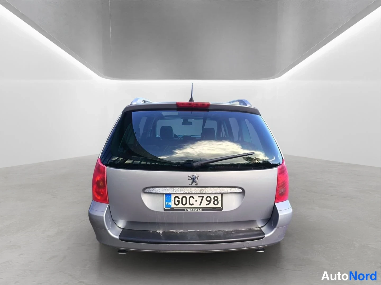 Takaa: Peugeot 307 -farmari suoraan takaa kuvattuna; rekisteritunnus, suuret takavalot ja kattokaiteet näkyvät.