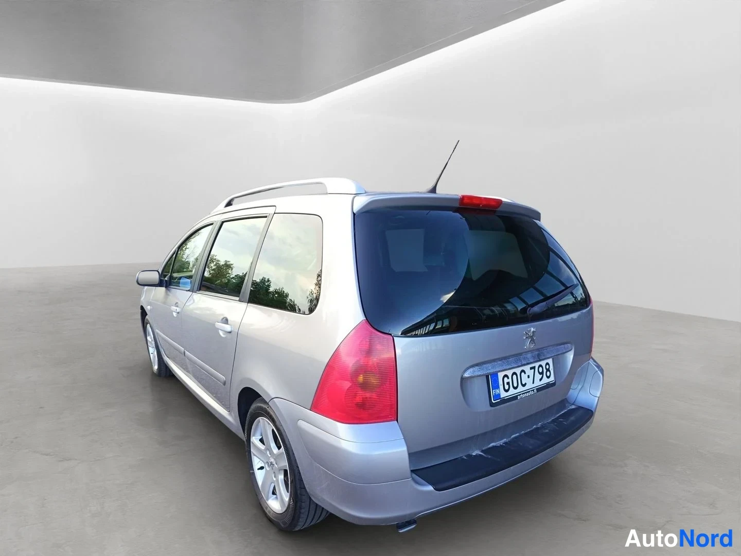 Takaviisto: Peugeot 307 -farmariauto takaa sivusuunnasta kuvattuna; rekisteritunnus ja kattokaiteet näkyvät. Auton kori on hopeanvärinen.