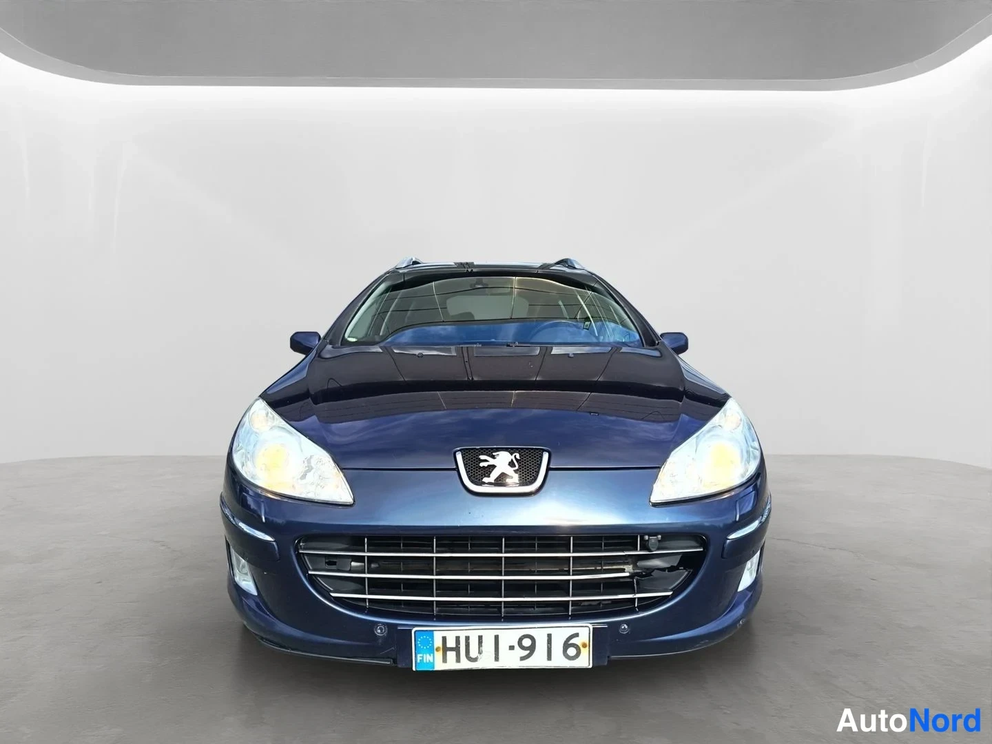 Edestä: Tummansininen Peugeot 407 farmari suoraan edestä, rekisterikilpi.