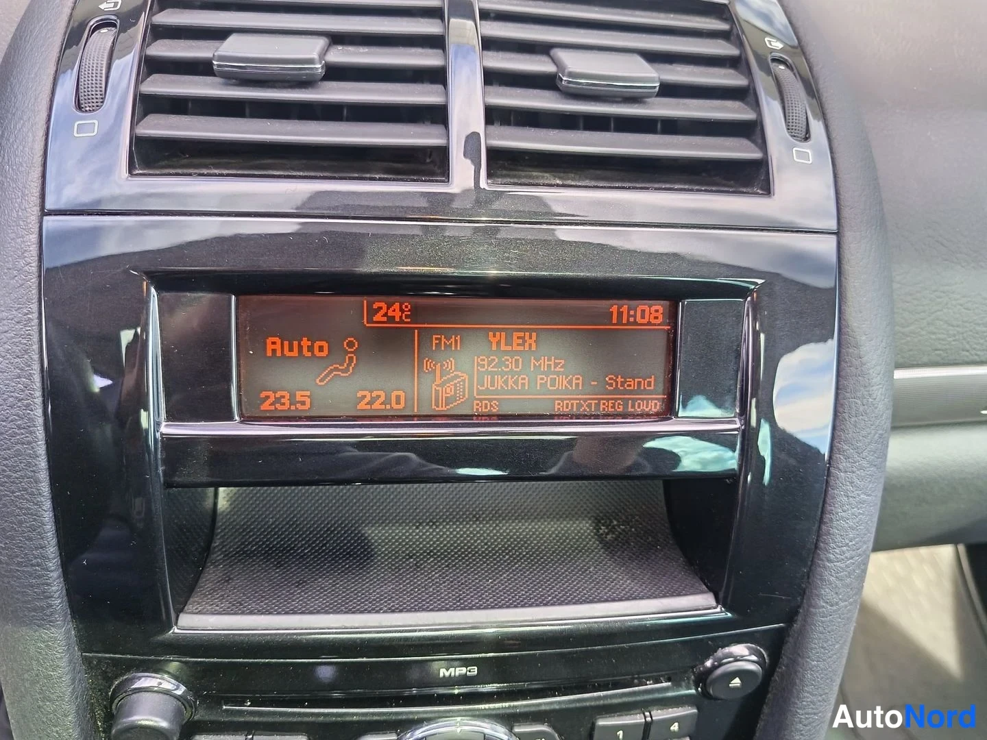 Muu: Kojelaudan infonäyttö, jossa näkyy radio YLEK 92.30 MHz FM1 -taajuudella, ohjelmanumerotiedot, kellonaika 11:08 ja lämpötilat 23.5 / 22.0.