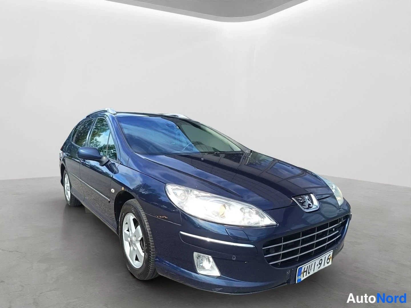 Etuviisto, nokka oikealle: Tummansininen Peugeot 407 -farmari kulmassa edestä oikealta, rekisterikilpi.
