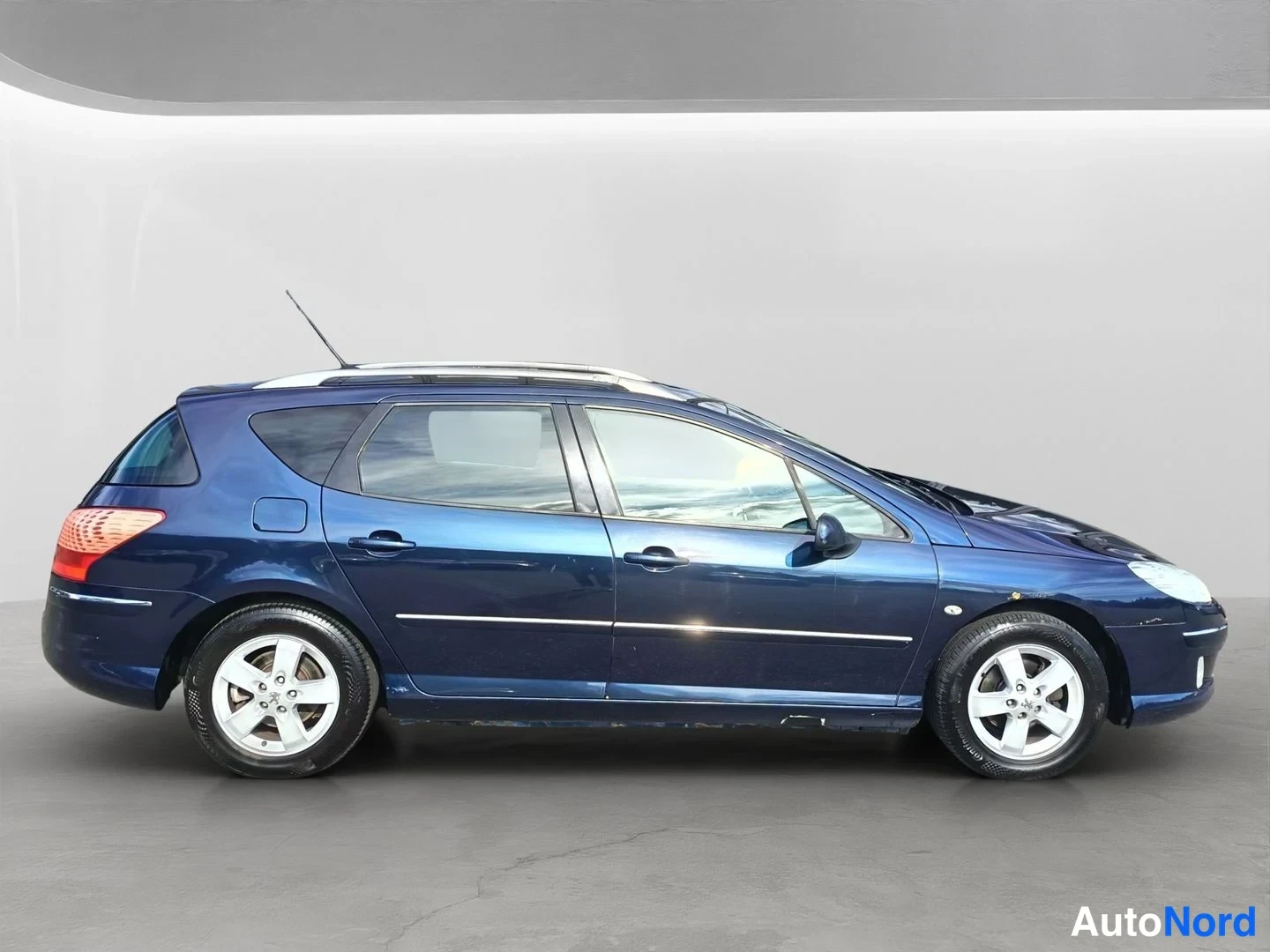 Takaviisto: Tummansininen Peugeot 407 -farmarin kylki ja takapää hieman takaa vasemmalta.