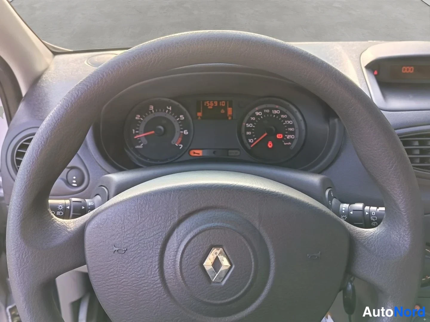 Yksityiskohta: lähikuva Renault-ohjauspyörästä ja mittaristosta, joka näyttää 156 910 km matkan, kierroslukumittarin ja nopeusmittarin asteikot.