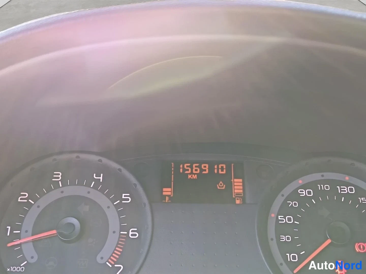 Yksityiskohta: lähikuva mittariston näytöstä, joka näyttää lukeman 156 910 KM.