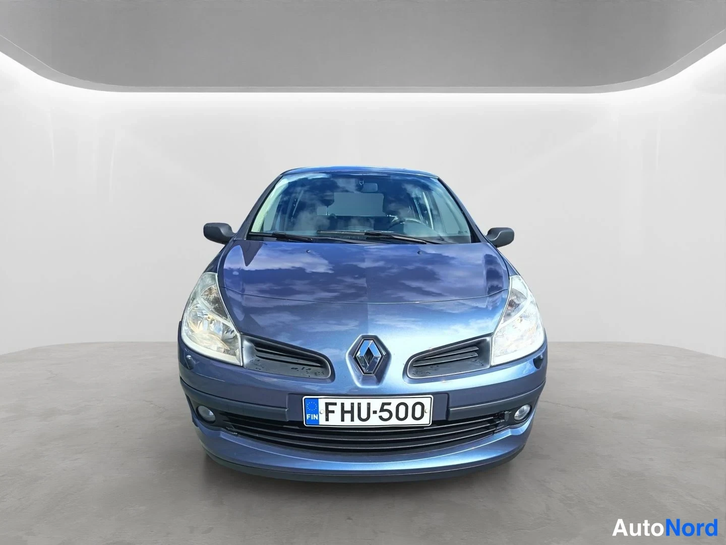 Edestä: Sininen Renault Clio suora etunäkymä, Renault-merkki säleikössä ja rekisterikilpi.