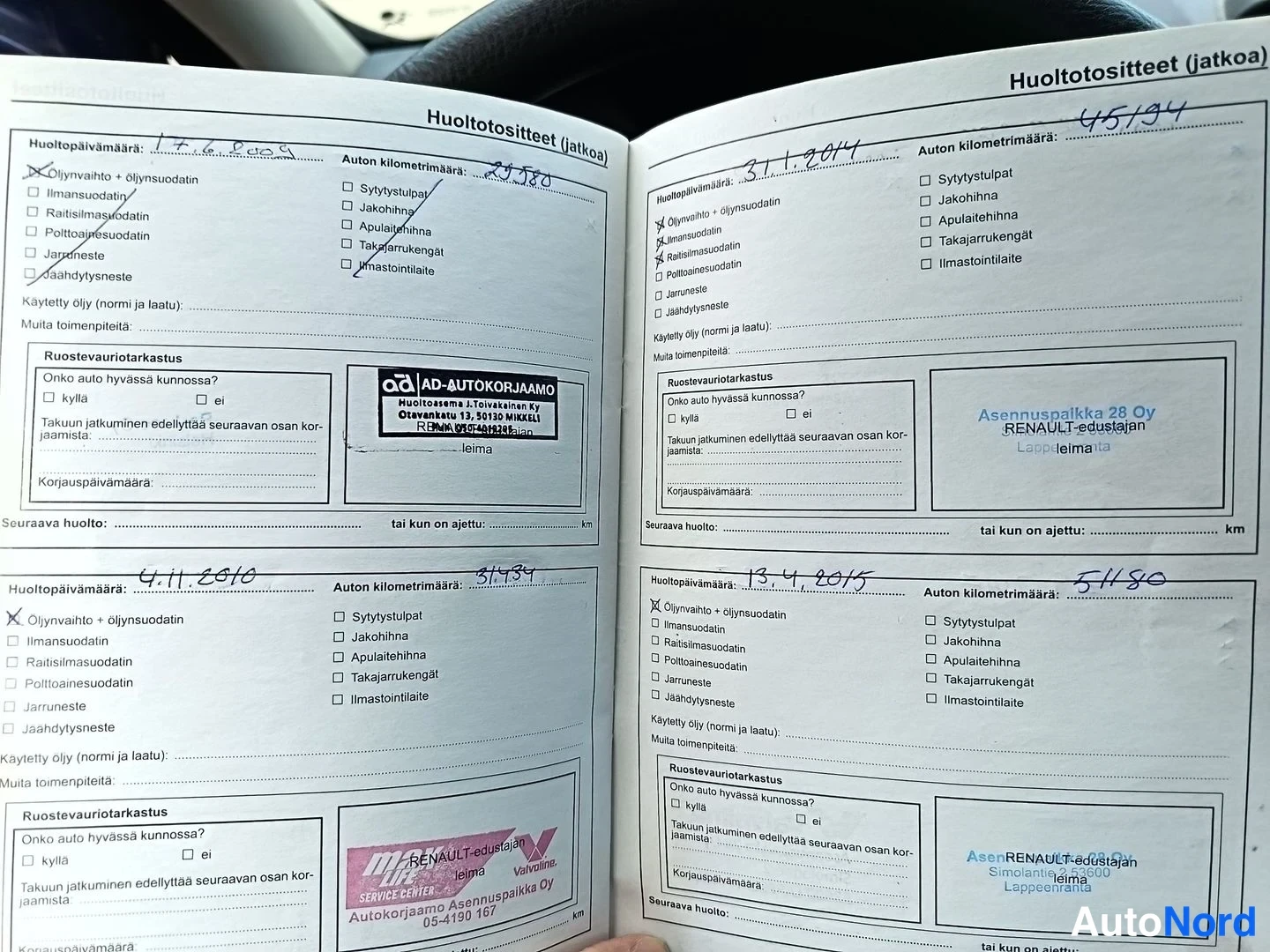 Asiakirja: Auki oleva huoltokirjan sivut. Näkyvissä huoltotietoja vuosilta 2010 ja 2014. Sinettiä ja leimaa sisältävä asiakirja 'AD-AUTOKORJAAMO'