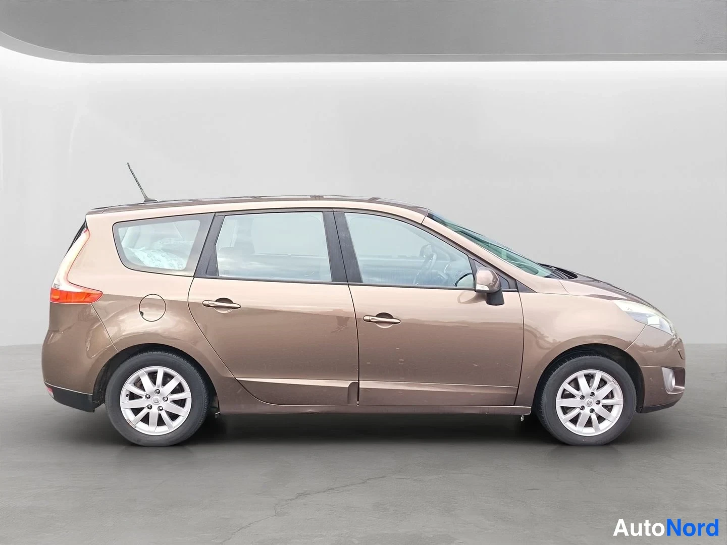 Sivulta: Ruskea Renault Grand Scenic kuvattuna suoraan sivulta. Näkyvissä koko kylki, ovet, tankkausluukku, kattotutka ja alumiinivanteet.
