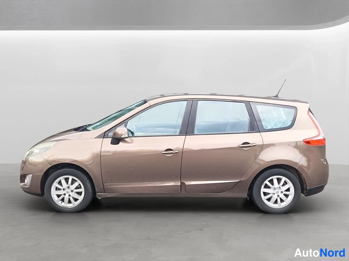 Sivulta: Ruskea Renault Grand Scenic sivulta oikealta kuvattuna; viisteenä näkyvät etu- ja takakulmat, kyljen kaksi ovea ja hopeiset 16 tuuman pyörät.