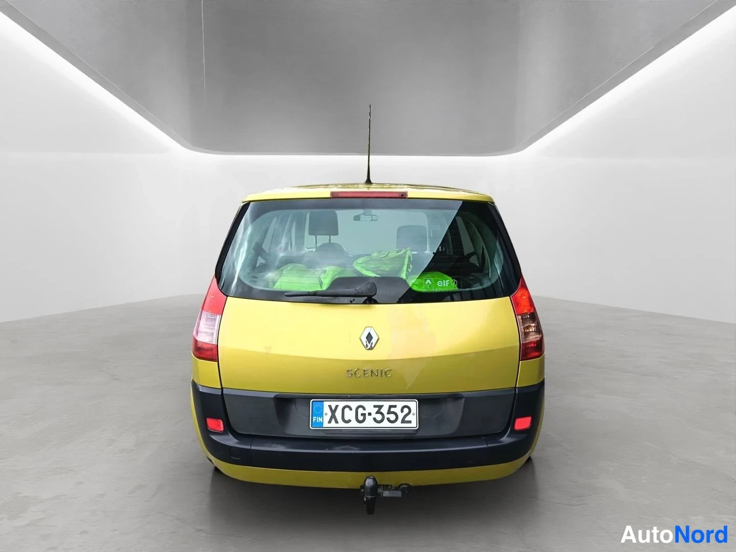 Takaa: Renault Scenic -auto suoraan takaa kuvattuna keltainen, takana koukku ja rekisteritunnus.