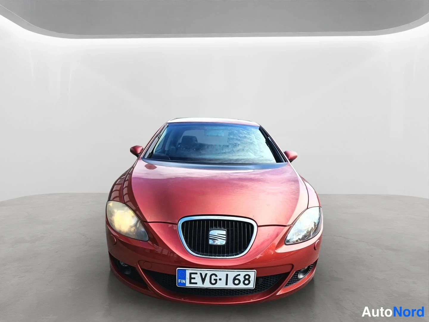 Edestä: Punaisen Seat Leon -henkilöauton etunäkymä suoraan edestä, rekisterikilpi.