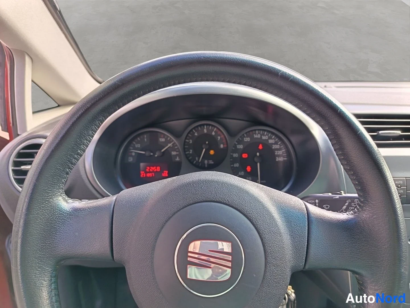 Edestä: Ohjauspyörän ja mittaristön lähikuva: SEAT-merkki keskellä, kiertokirjain näytöllä lukee 2258, nopeusmittari asteikolla jopa 240 km/h.