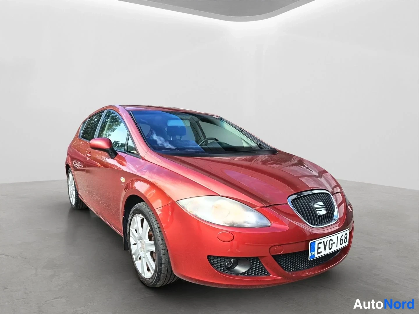 Etuviisto, nokka oikealle: Punainen Seat Leon kuvattuna etuviistalta oikealta, rekisteri, studiossa.