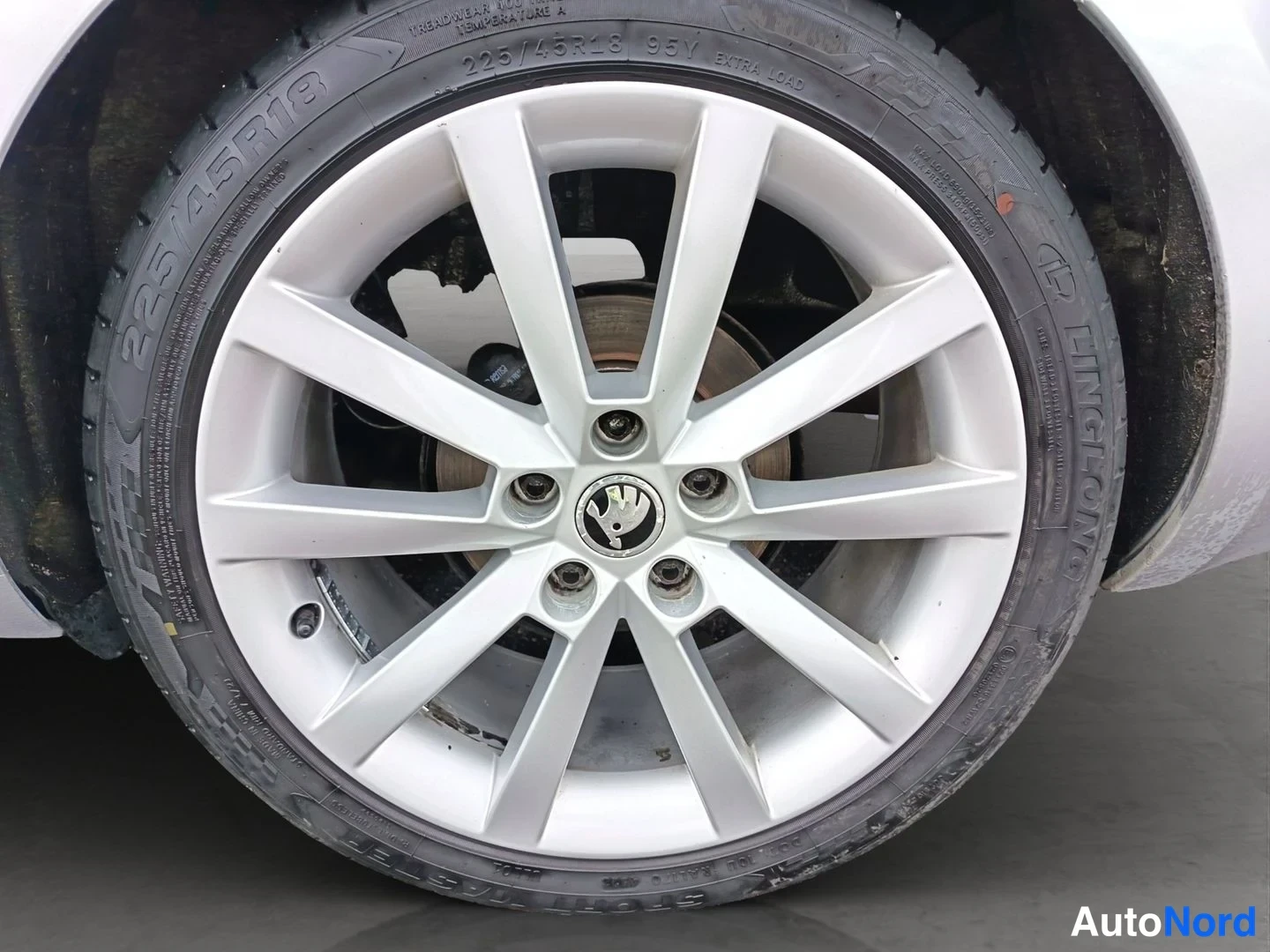 Muu: Lähikuva auton hopeanvärisestä kevytmetallivanteesta ja renkaasta, jonka sivuseinässä lukee 225/45R18 95Y.