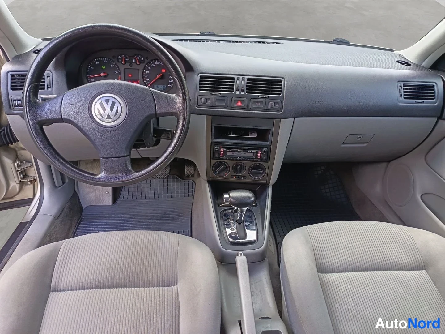 Ohjaamo: Kahdesta tuolista koostuva sisäkuva etuistuimen takana. Ohjauspäässä on Volkswagen logo ja taustalla mittari ja radioyksikkö ovat näkyvissä.