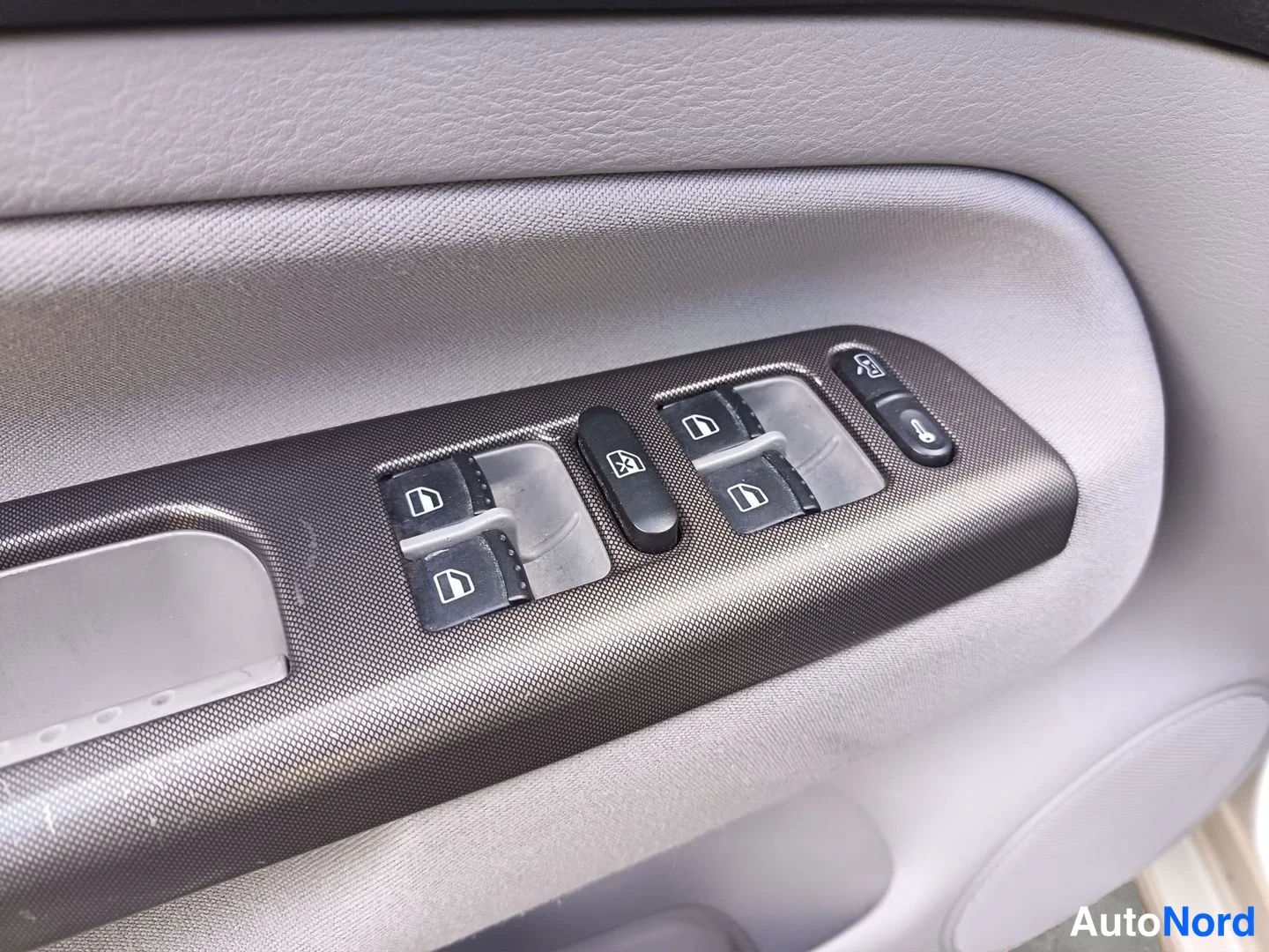 Ohjaamo: Interior door panel control module for the driver's side window switch. Visible controls include window up/down switch, rear window lock button, mirror adjustme