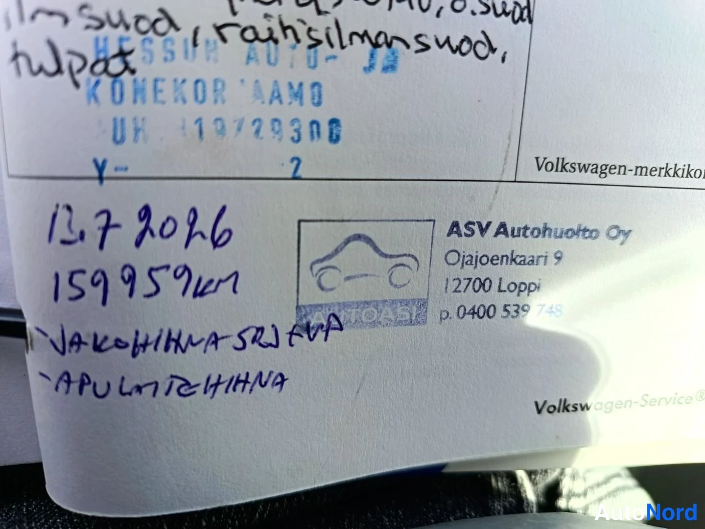 Yksityiskohta: Volkswagenin huoltokirjan merkintasivu lähikuvassa, käsin kirjoitetut merkinnät 13.7.2026 ja ASV Autohuolto Oy:n leima.